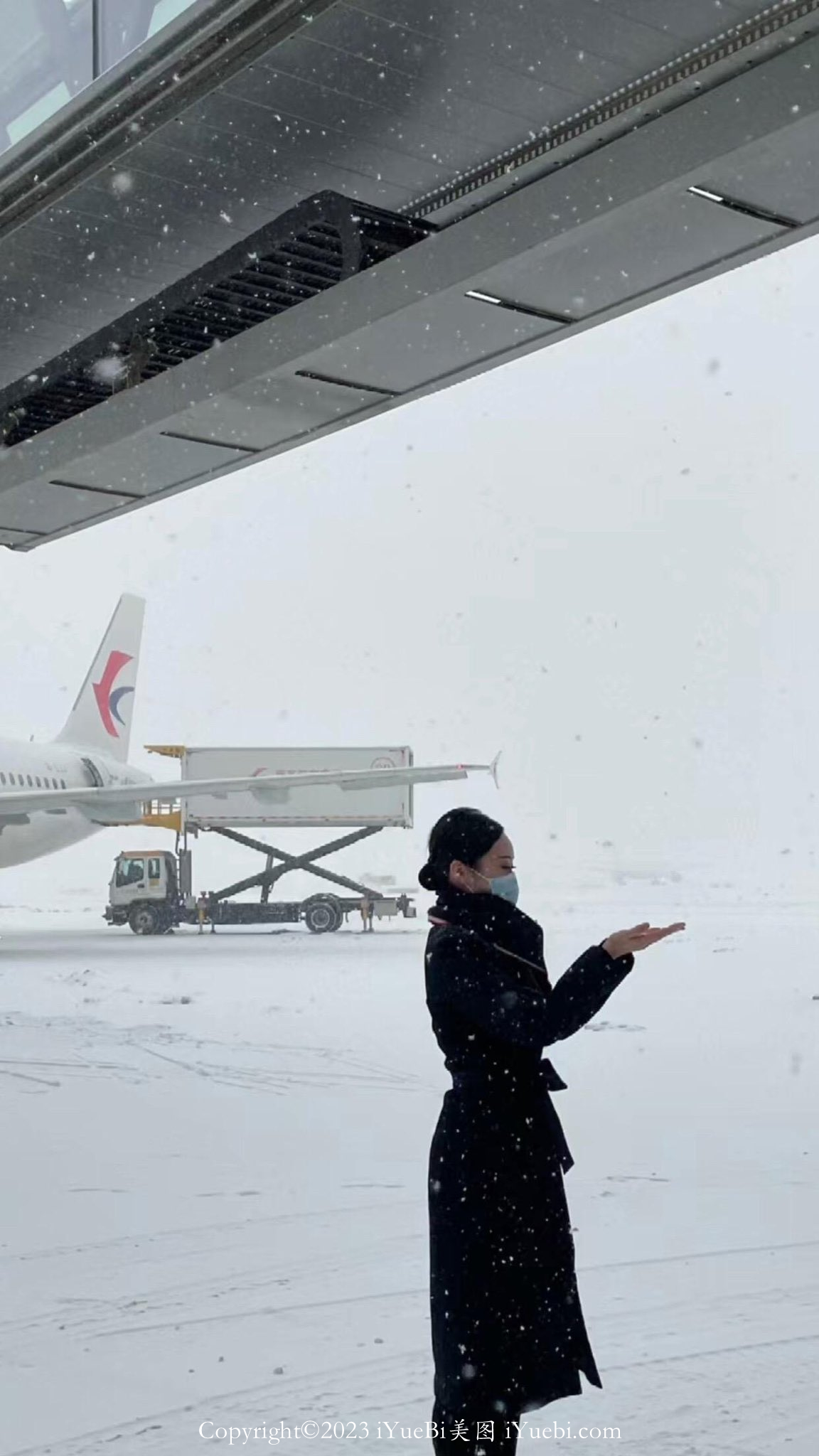 机场停机坪上大雪中的一个南方航空空姐