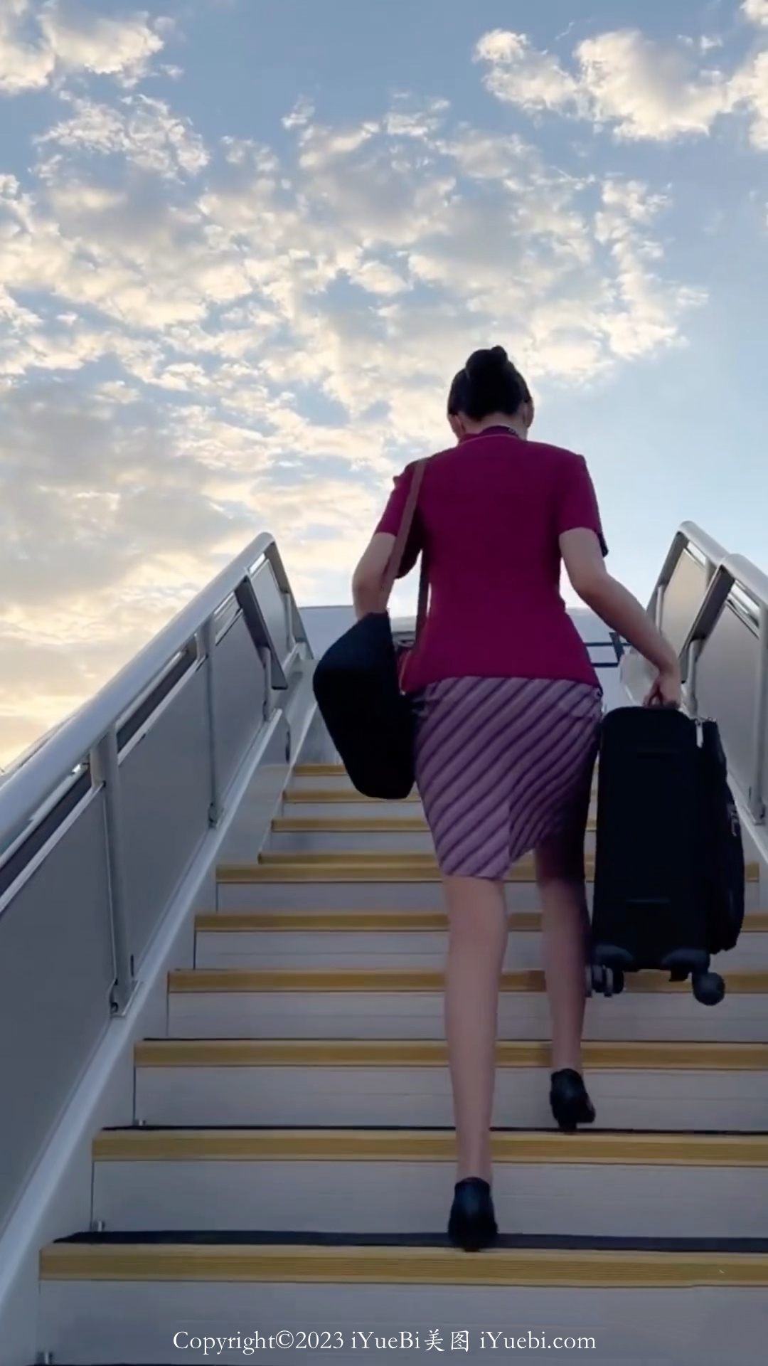 停机坪上拎着行李箱走上飞机的南航空姐背影